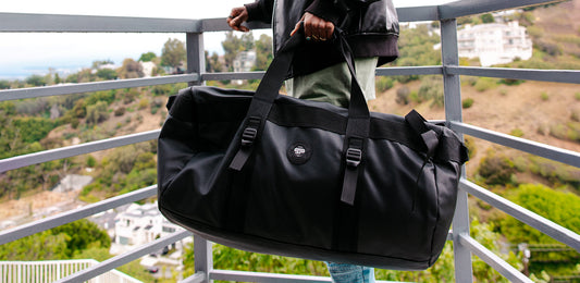 Woman standing on balcony holding large duffel bag