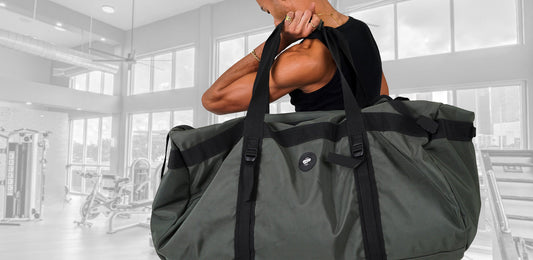 Man standing in gym with large L200 Transporter duffel bag