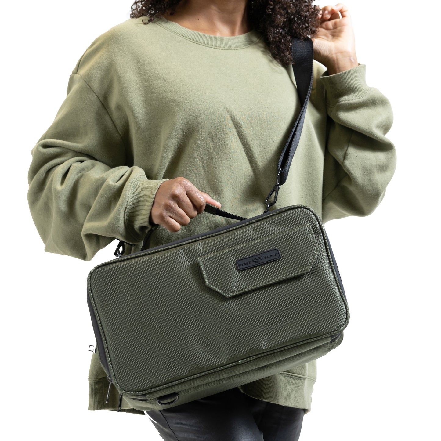 Women with green sweater and curly hair holding Stash Box in Green by crossbody harness by Stash Proof on white background.