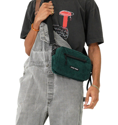 Male model from shoulder down in gray overalls carrying dark green Rover bag