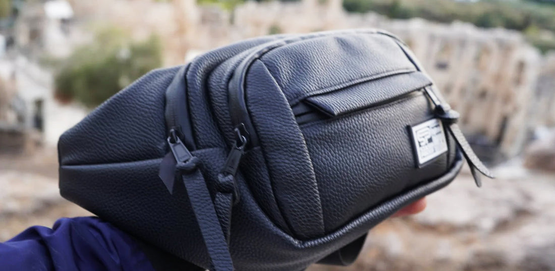 Transporter fanny pack and crossbody being held up in nature backdrop