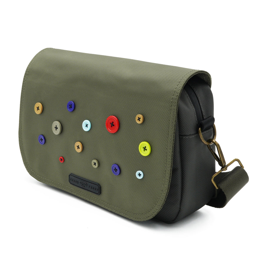 Side view of the Button Bag showing its brass D-ring, shoulder strap, and main flap