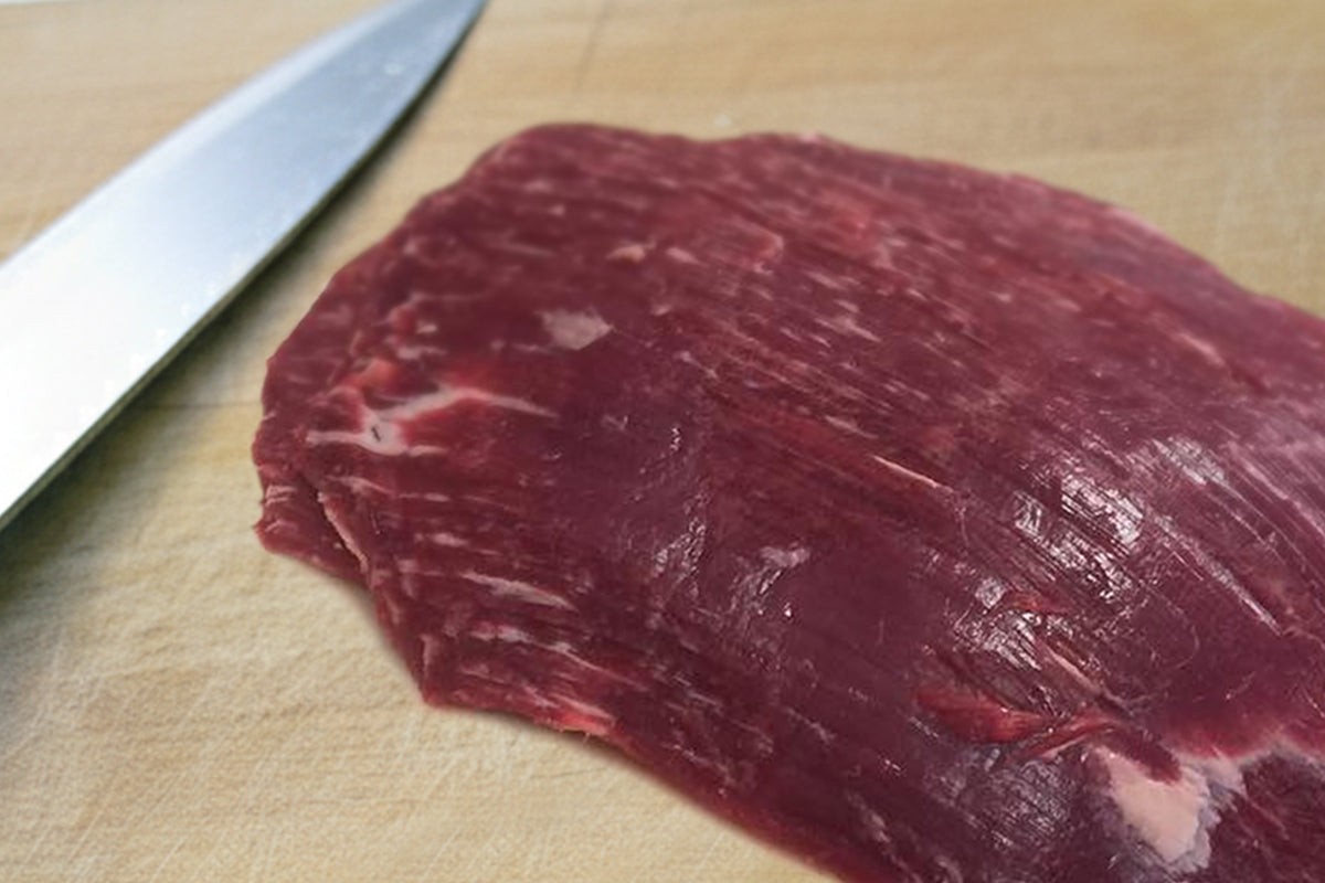 Raw beef on a cutting board with a knife