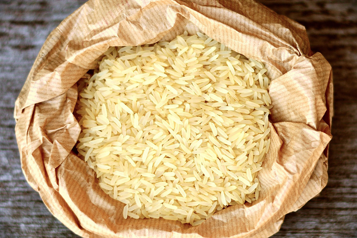 Uncooked rice in a brown paper bag on a wooden surface