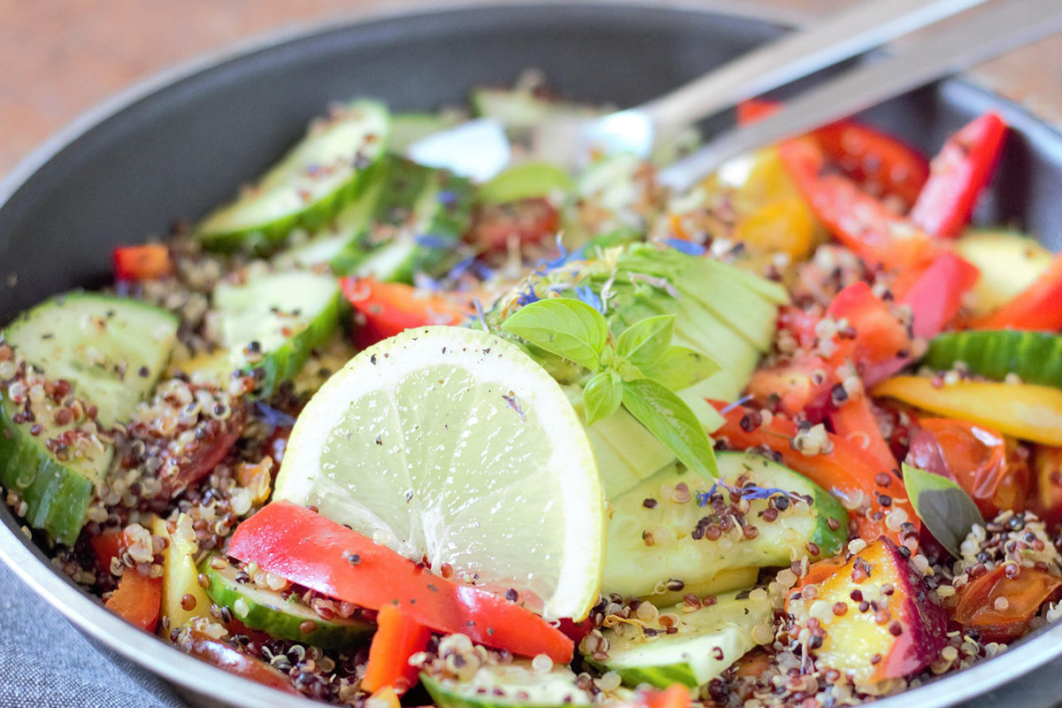 Colorful salad with quinoa, cucumbers, and bell peppers in a pan.