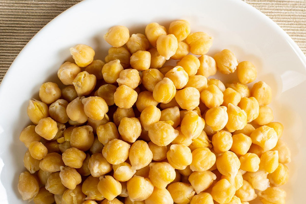 White bowl filled with chickpeas on a tan woven place mat