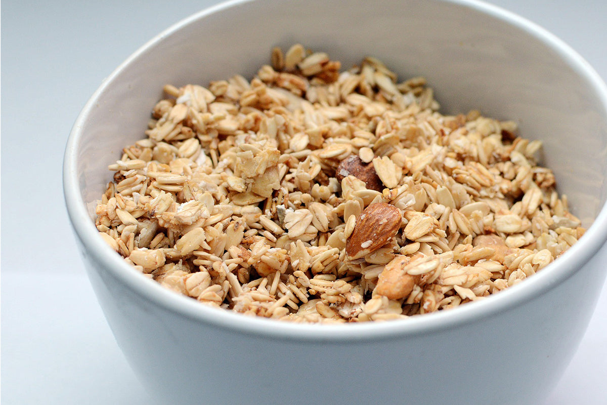 White bowl filled with granola on a light blue background