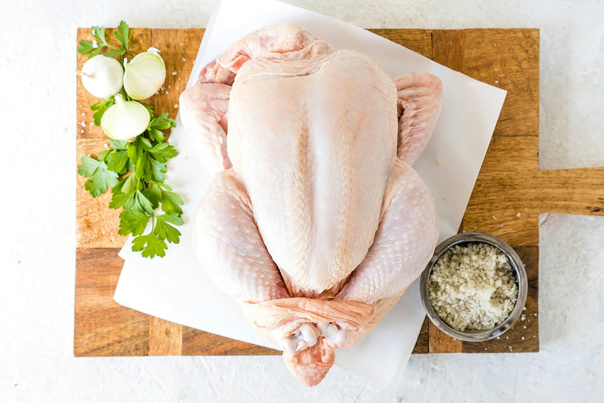 Raw chicken on a cutting board with herbs and spices