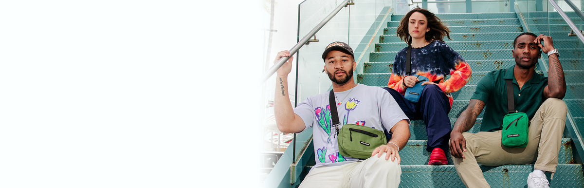 Three people sitting on a staircase with various colorful bags