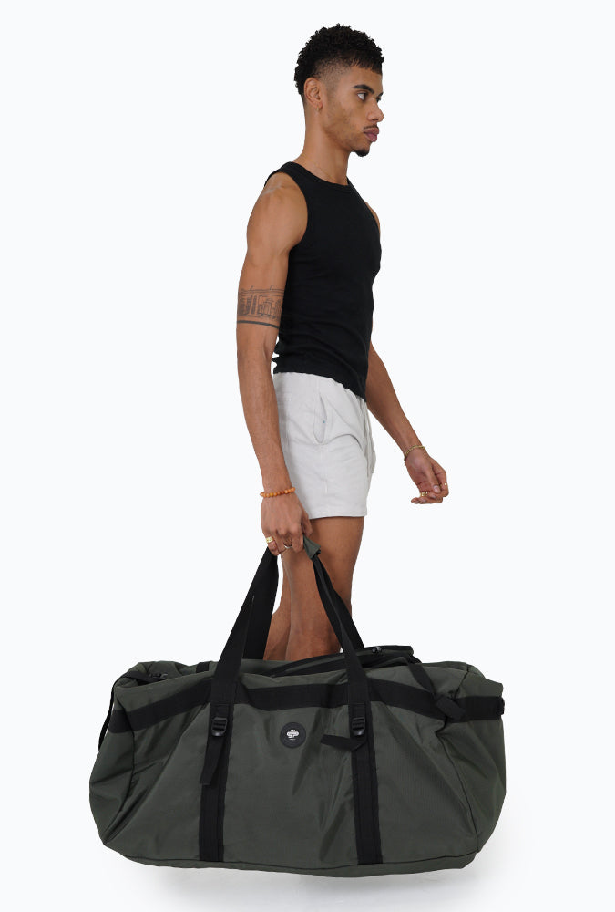 Man carrying XL Transporter Duffel Bag by carrying handles on white background