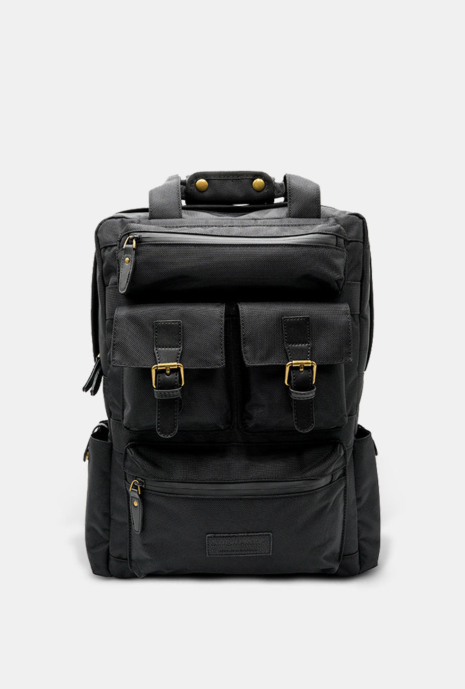 Black Runner backpack with brass buckles on a light gray background