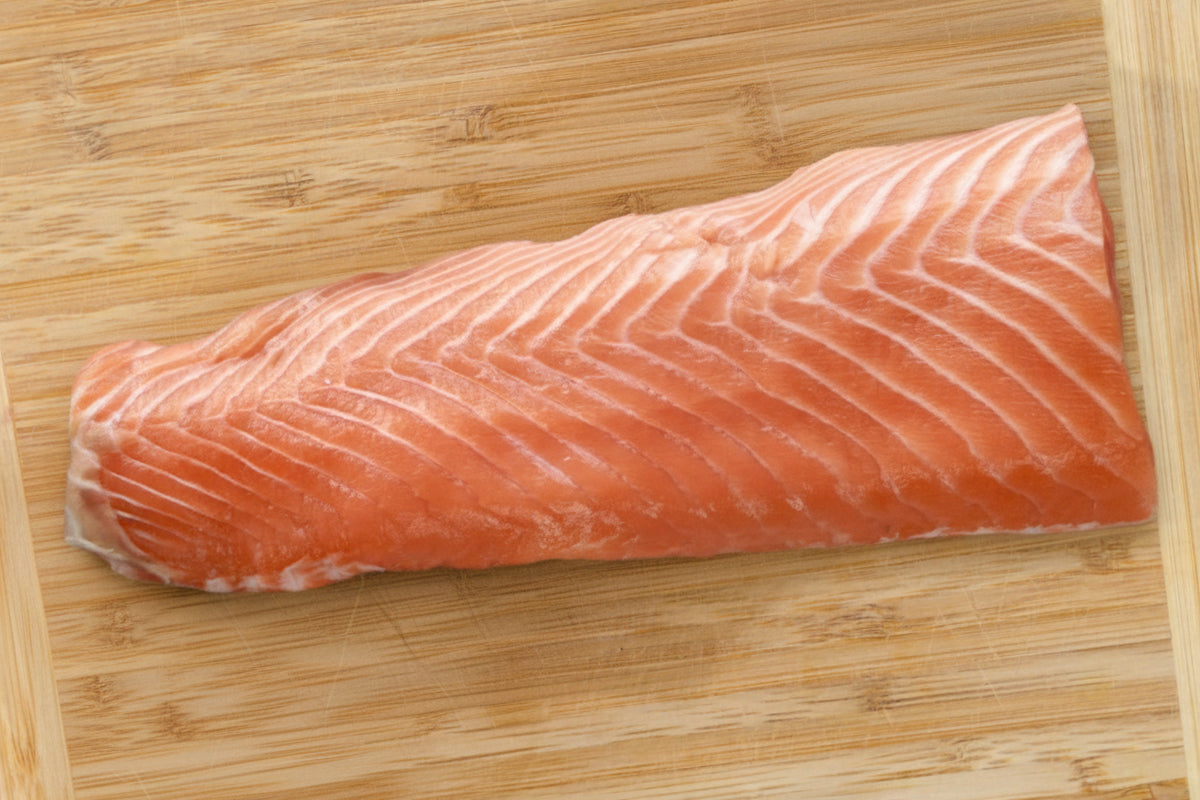 Raw salmon fillet on a wooden cutting board