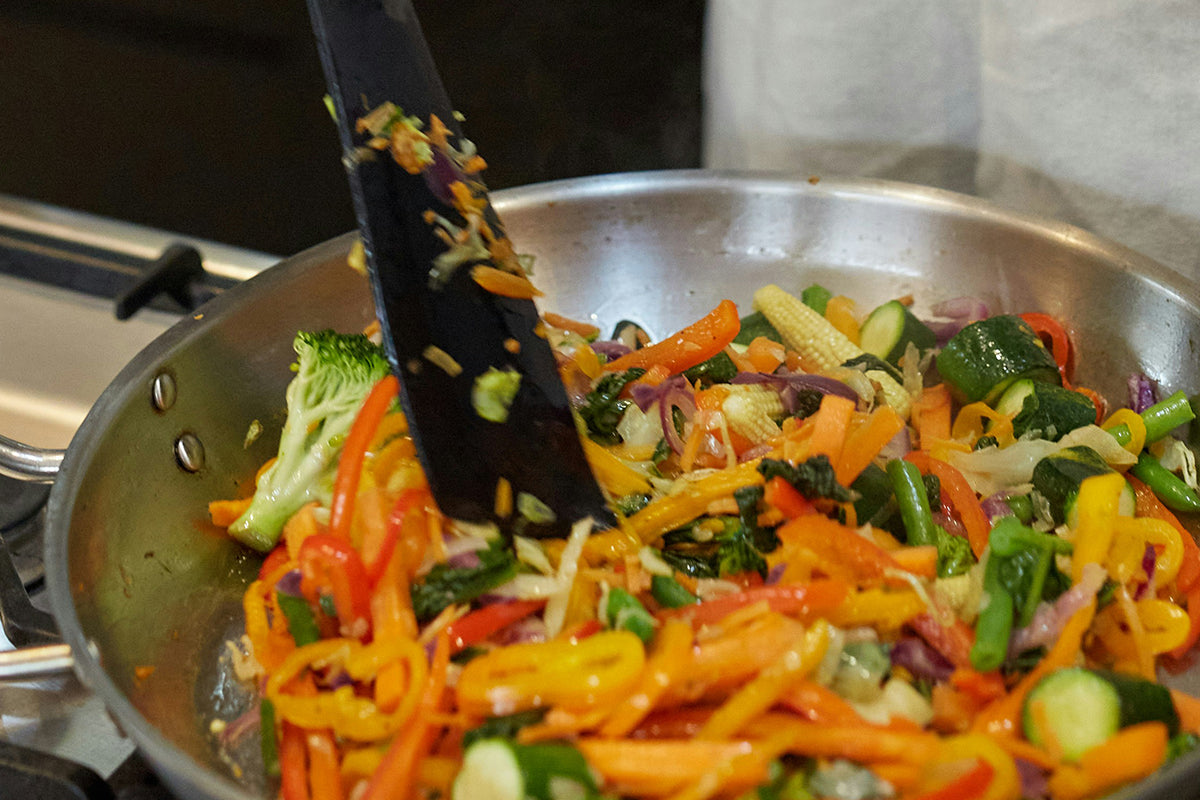 Colorful stir-fry in a pan with vegetables and a spatula.