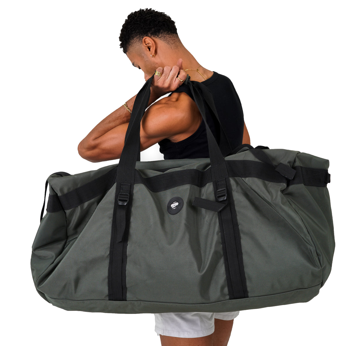 Person carrying the olive Transporter XL200 by its reinforced duffel handles to show its extra-large scale
