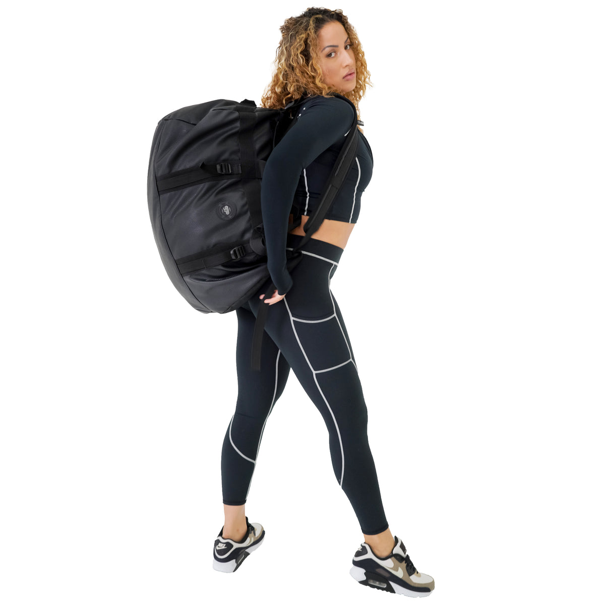 Woman carrying the black Transporter L100 as a backpack to show its large scale and padded straps