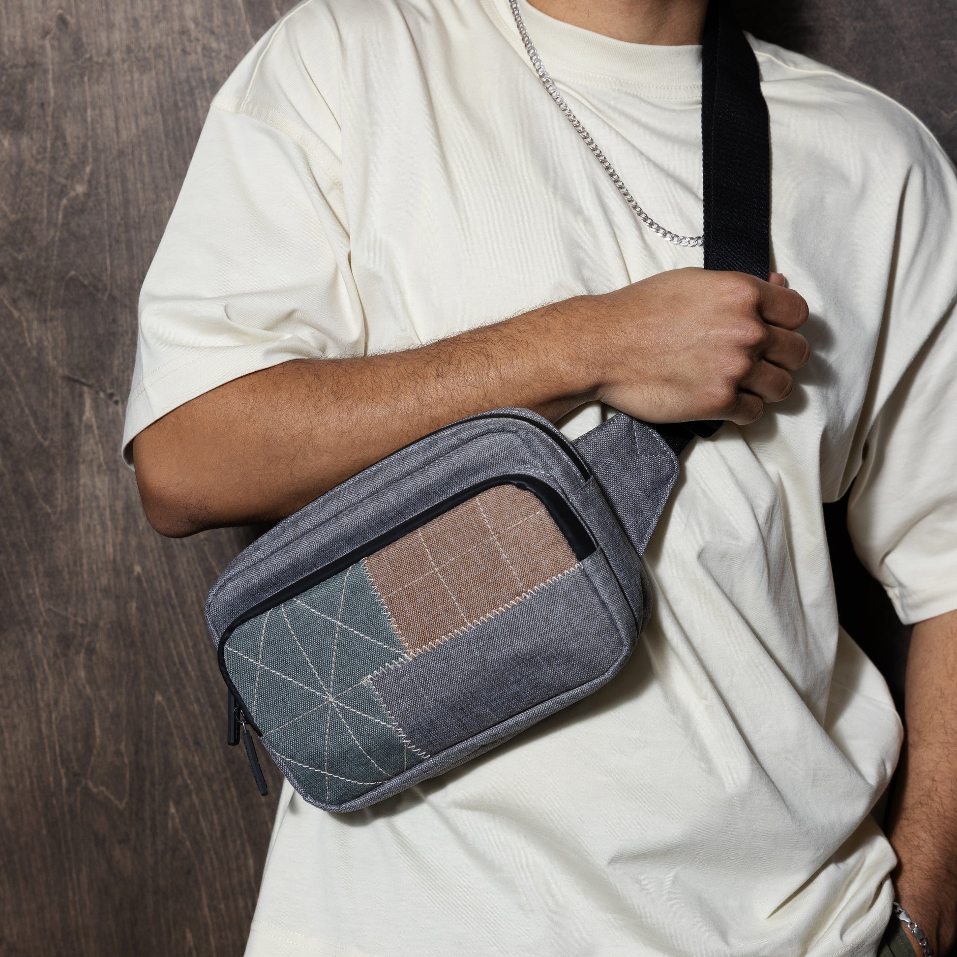 carrying a gray earth tone crossbody bag with patchwork design and a off white shirt