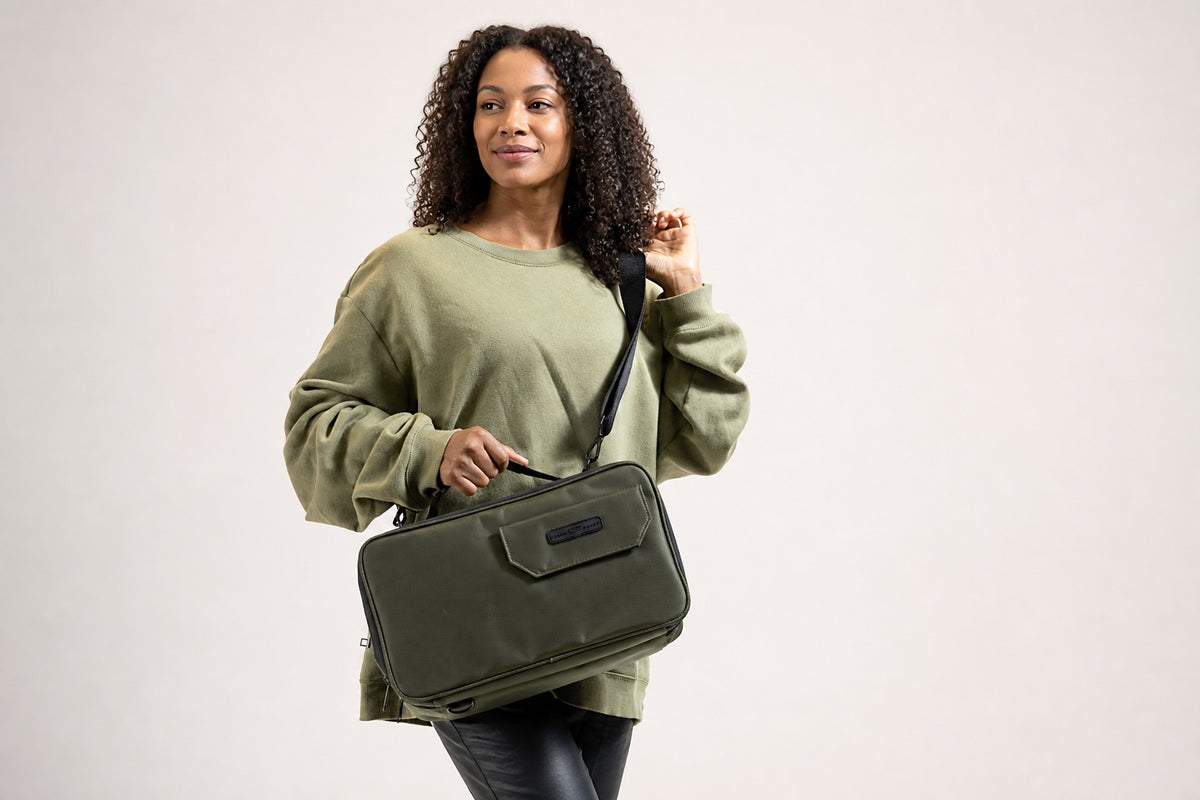 Woman carrying the olive green Stash Box with its detachable shoulder strap